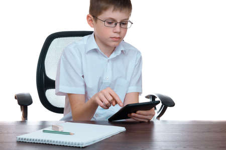 Cute teenager boy watching movie on tablet computer isolated on white background.