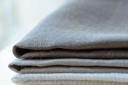 Horizontal shot of grey towels pile isolated on wooden background.