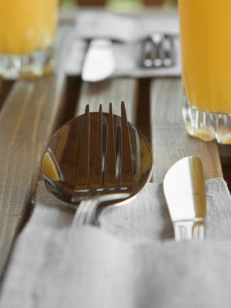 Vertical shot of Cutlery in linen napkin, juice on wooden table, set for twoの写真素材