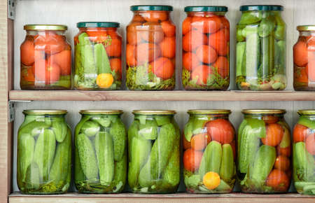 Glass jars with home canned vegetables standing in rows on wooden shelves.の写真素材