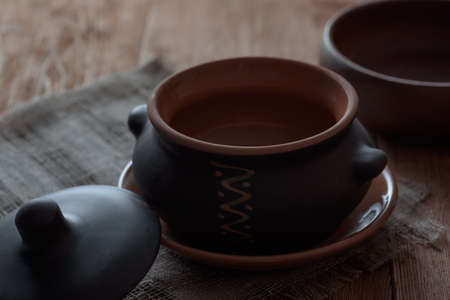 The horizontal shot of empty roasting pot in the oven on the table covered with linen napkin....