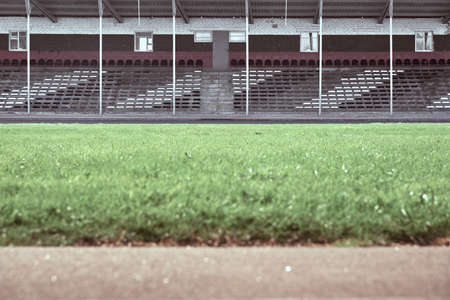 Empty audience seats at the stadium. In the foreground is a green field in blur.の写真素材
