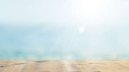 Horizontal shot of terrace at Ocean. Wooden empty table lit by soft sunlight in blur. Blurred blue sea background.の写真素材