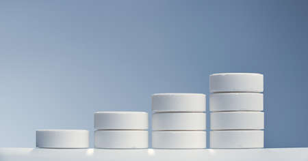 Horizontal shot of straight stack white pills with different sizes macro isolated on a gray background.の写真素材