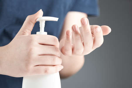 Horizontal shot of hands using hand sanitizer gel pump dispenser.の写真素材