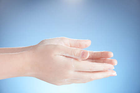 Washing teenager hands isolated on blue background.