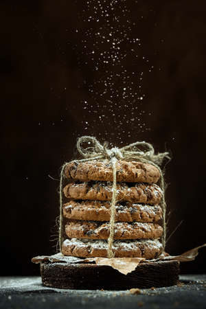 Vertical shot of round cookies in a stack tied with a rope are sprinkled with powdered sugar on a brown background.の写真素材