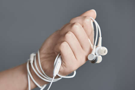 Horizontal shot of headphones in his fist. The wire binds the hand. The concept of dependence on headphones.の写真素材