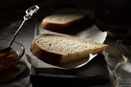 Breakfast with bread and fruit jam on wooden table in the shadow.