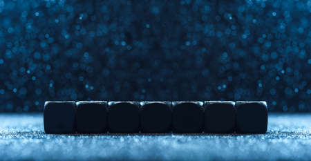 Horizontal shot of black seven cubes on a blue background. Photo with copy space.