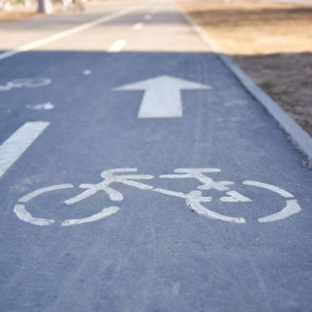 Square shot of bicycle symbol on city street in the evening. The background in blur.