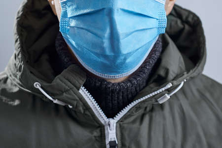 Horizontal shot of man in a protective mask close-up in a jacket on a gray background.の写真素材