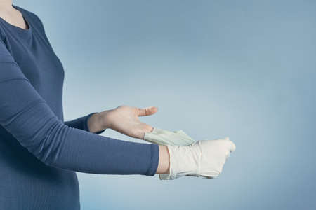 Horizontal shot of girl puts off the medical blue gloves, isolated blue background.