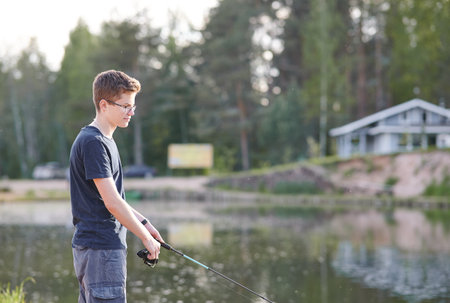 Horizontal shot of young Man fishing on Lake with rod . Travel Lifestyle concept summer vacations.の写真素材