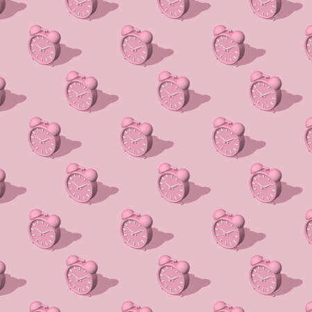 Pink alarm clocks big and small with shadow on pink background. Long shadow from the summer...