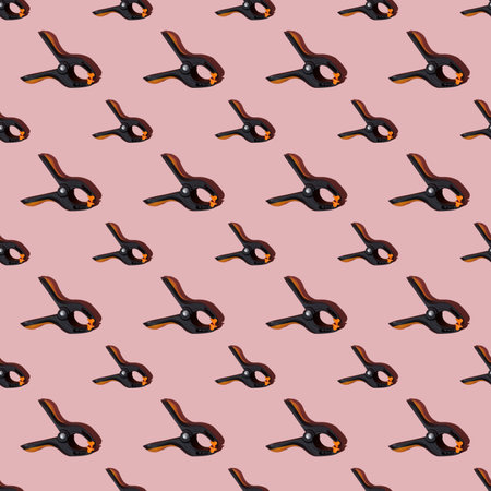 Seamless pattern of black multipurpose clamps with orange grips. Pink background.の写真素材