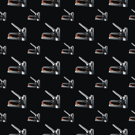 Seamless pattern of construction staplers on a black background. Background for the design.の写真素材