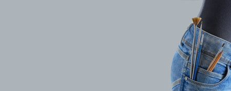 Horizontal banner of brushes and pencils in the pocket of the girl's jeans on a gray background. artist painting concept.の写真素材