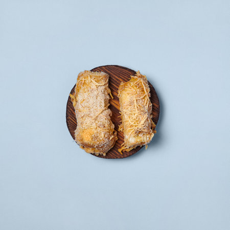 Square shot of zucchini in batter, fried and baked on a wooden round board isolated on blue background.の写真素材