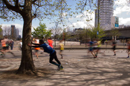 London, United Kingdom. 24 april, 2016. A runner from the Virgin Money London Marathon 2016 rests leaning against a tree.のeditorial素材