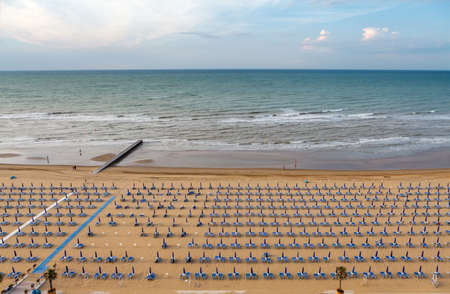 Rows of blue and white parasols and sunbeds on the beach at Lido di Jesolo, Italy.