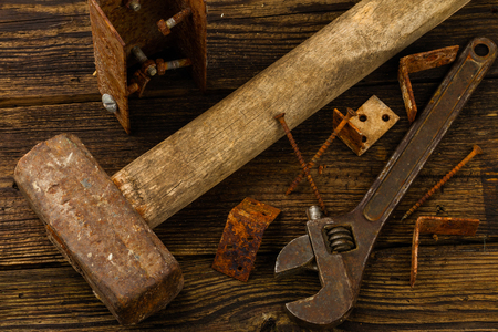 corner braces, screws, screwdriver, sledge hammer and adjustable wrench on wooden backgroundの写真素材