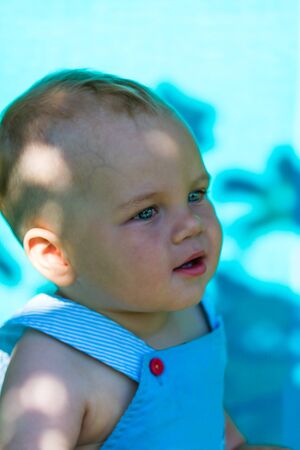 charming caucasian baby boy on chaise lounge in parkの写真素材