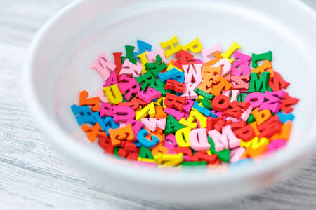 multicolored wooden letters in a plate, eating knowledge, English letters dyeing in different colorsの写真素材