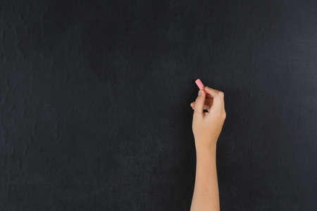hand writing chalk on a blackboard in the classroom, a child writing on a school chalkboard with chalk, a summer schoolの写真素材