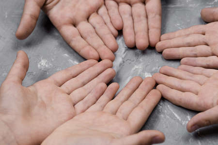 children's hands together in a circle with their hands up on a gray background, top view. joint support and assistance in the communityの写真素材