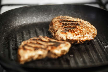 meat with beautiful roast in pan is fried at home, two small pieces of steak with spices are cooked in hot ribbed panの写真素材