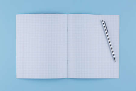 school notebook with pen on a blue table top view, office desktop, office supplies on a light blue...