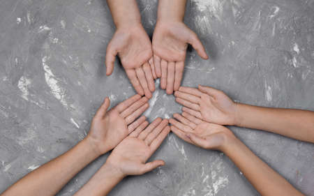 children's hands together in a circle with their hands up on a gray background, top view. joint support and assistance in the communityの写真素材