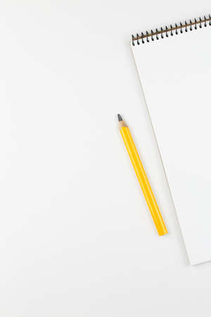 open notebook with yellow pencil on white table top view, spiral notepad with blank page. flat lay of office concept, vertical viewの写真素材