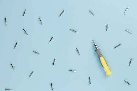 table of a master with scattered nozzles on a screwdriver, pattern of tools on blue background top...