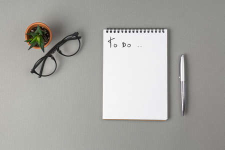notebook, pen, coffee cup, glasses to do list on a gray background. Office concept. Top view.の写真素材
