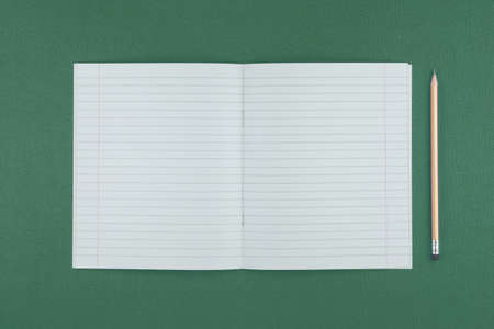 school notebook with a pencil on green table top view, office desktop, office supplies on a light...