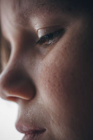 little girl cries emotional portrait, child is upset, picture with backlight and with noises for artistic purposesの写真素材