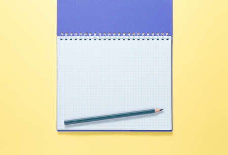 top view of a open notebook with pencil on yellow background, school notebooks with a spiral spring, office notepad flat layの写真素材