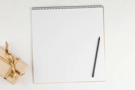 Gifts on blank notebook sheet on a white background, top view. Flat lay with copy space....