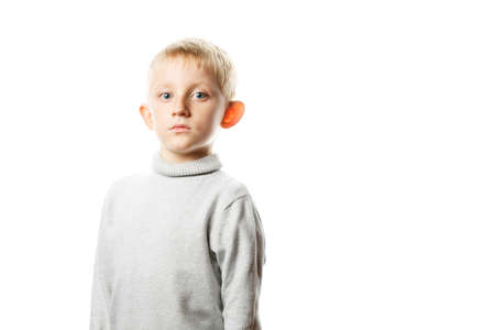 little boy in a gray sweater on white isolated background, child with serious face on white wall...