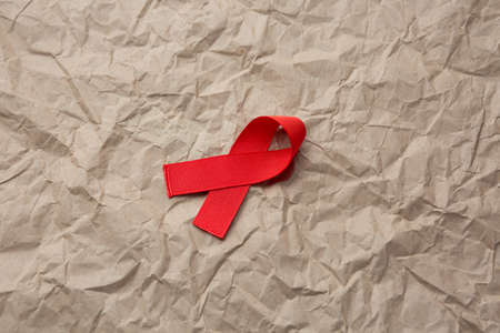 aids red ribbon on rumpled cardboard paper, hiv ribbon on kraft paperの写真素材