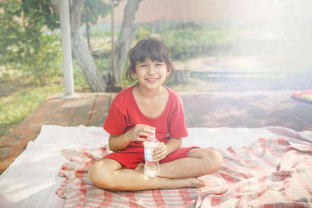 little girl with a bottle of water on the terrace on a sunny day. outdoor recreation for children...