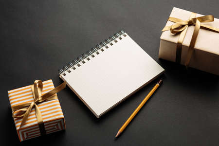 school notebook with gifts on a black background, gift boxes with spiral notepad on a table