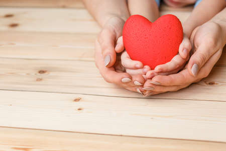 hands with red heart, top view on white and wooden backgroundの写真素材