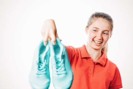 girl holds stinky sneakers and closes her hand with her nose, smell of shoes, photo on white isolated backgroundの写真素材