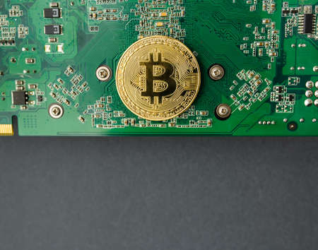 bitcoin on the video card, bitcoin coin on the table near the computer board, a lot of free spaceの写真素材