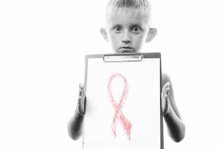 little boy holding a tablet with a red ribbon symbol combating cancer and AIDS, isolated on a white background. Day against HIV and Cancer.black and white.の写真素材