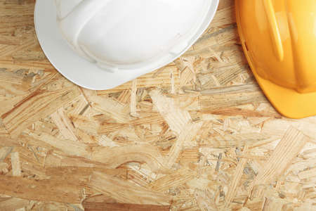 construction helmet on a wooden board top view. osb board as background flat lay.