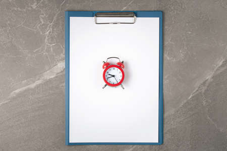 open notepad on the marble table with alarm clock, top view,business concept